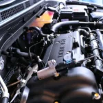 Mechanic comparing a dirty engine air filter and a cabin air filter near an open car hood