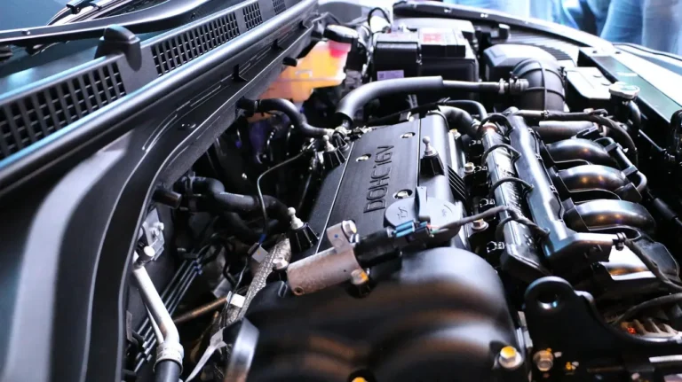 Mechanic comparing a dirty engine air filter and a cabin air filter near an open car hood