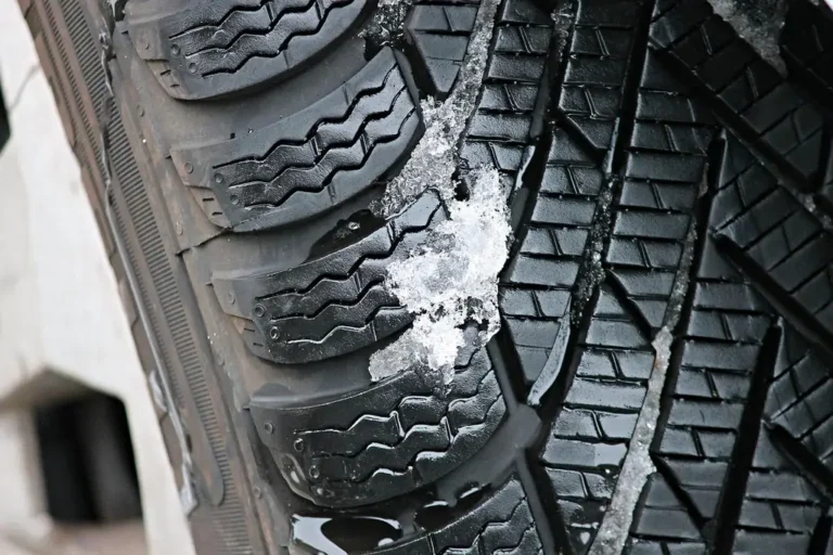 A sedan driving on a snowy road, showing all-season tires in winter conditions.
