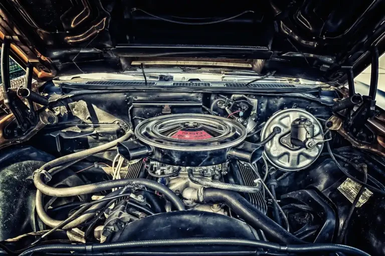 Mechanic checking a dirty car air filter next to a clean replacement under an open hood