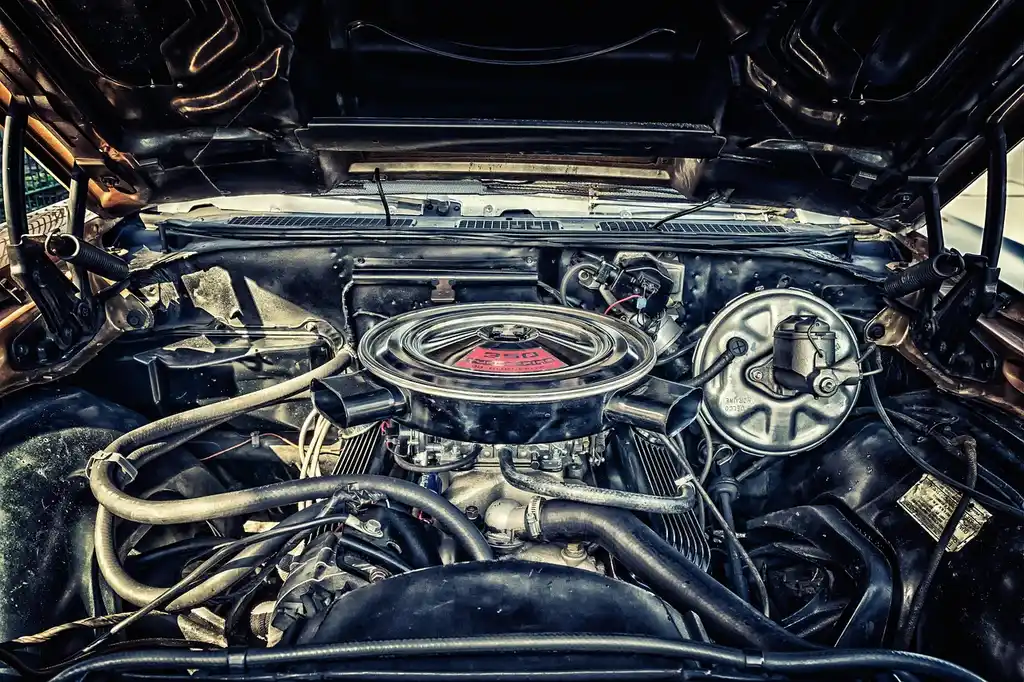 Mechanic checking a dirty car air filter next to a clean replacement under an open hood