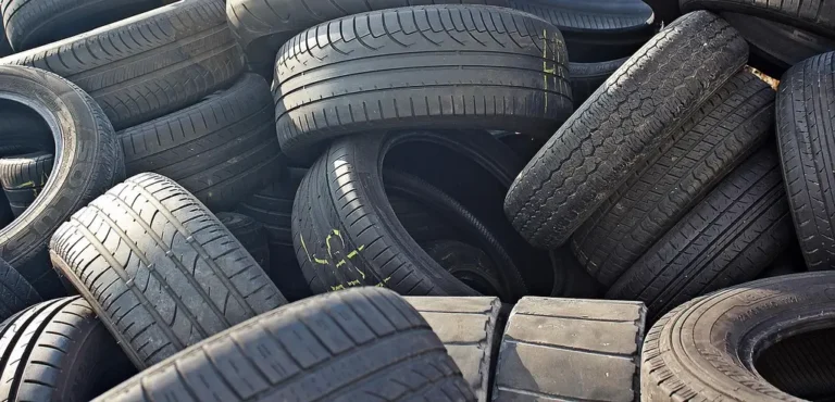 Mechanic checking tire tread on a sedan in a sunlit service bay