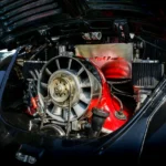 Car owner checks a dusty engine air filter beside an open hood in daylight