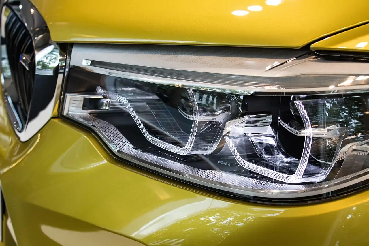 Modern car headlight assembly beside LED and halogen bulbs on a workbench