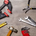 Mechanic comparing torque wrenches on a garage workbench beside fasteners and a wheel hub