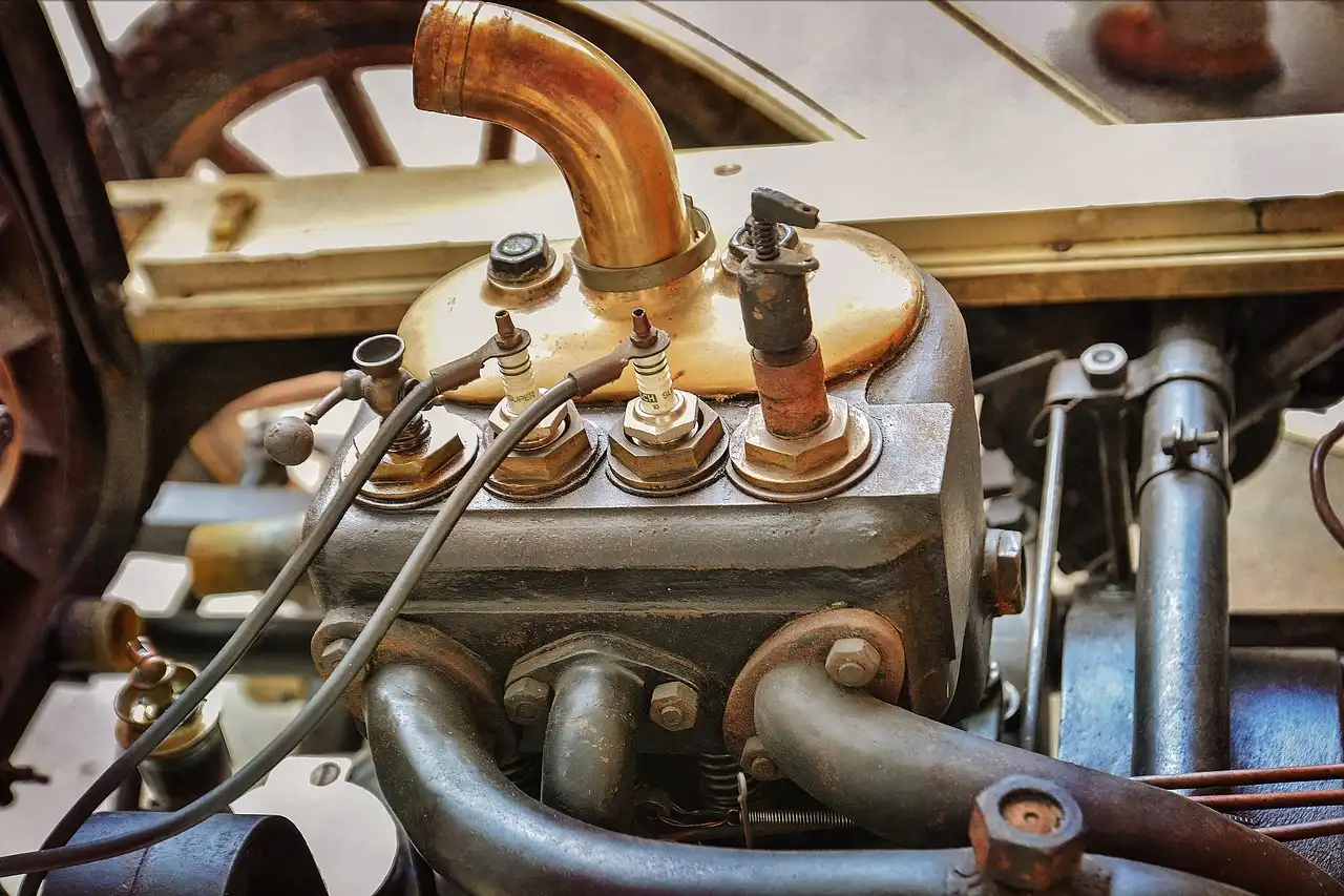 Mechanic inspecting a car engine bay near the spark plugs in natural daylight