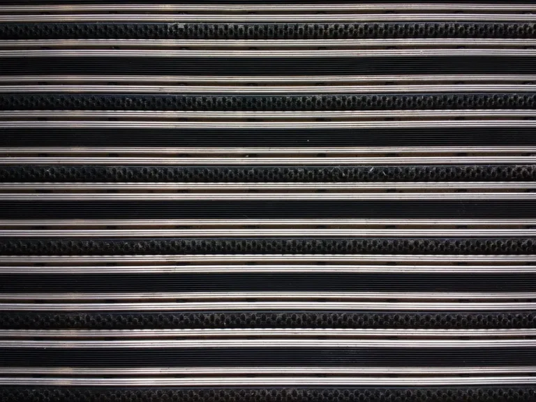 Car floor mats laid beside a vehicle footwell template and measuring tape on a garage workbench