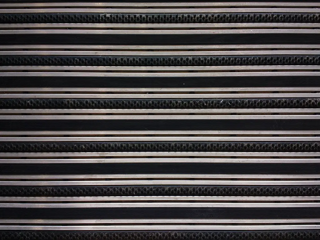 Car floor mats laid beside a vehicle footwell template and measuring tape on a garage workbench